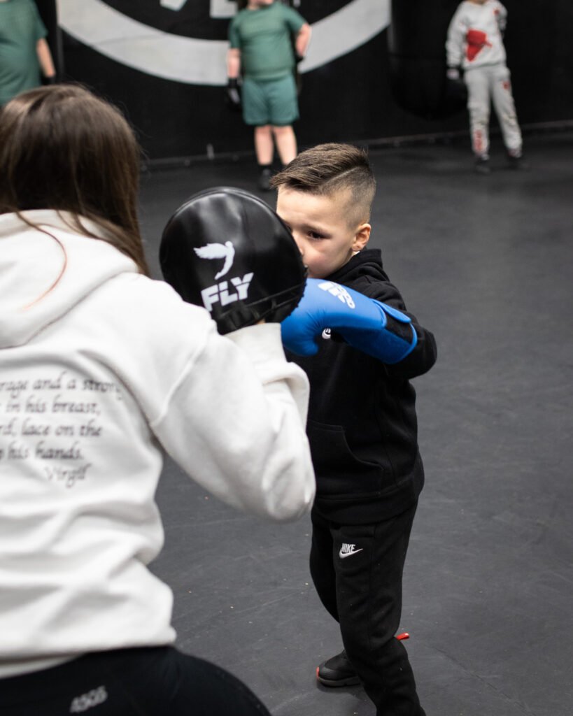 Young child at one of our kid's boxing classes working on the pads
